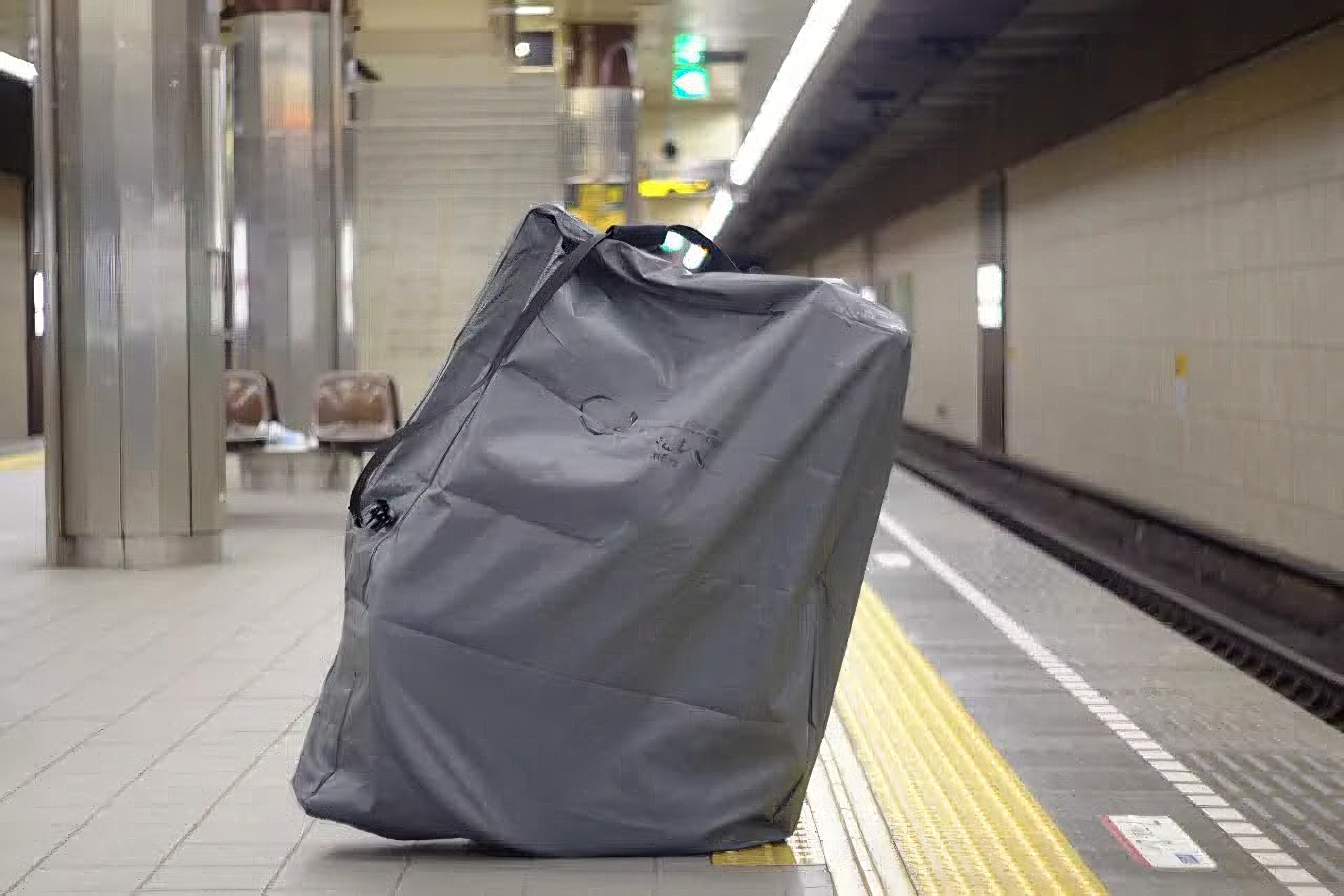 地下鉄の駅のホームに輪行袋に入ったロードバイクを置いた様子