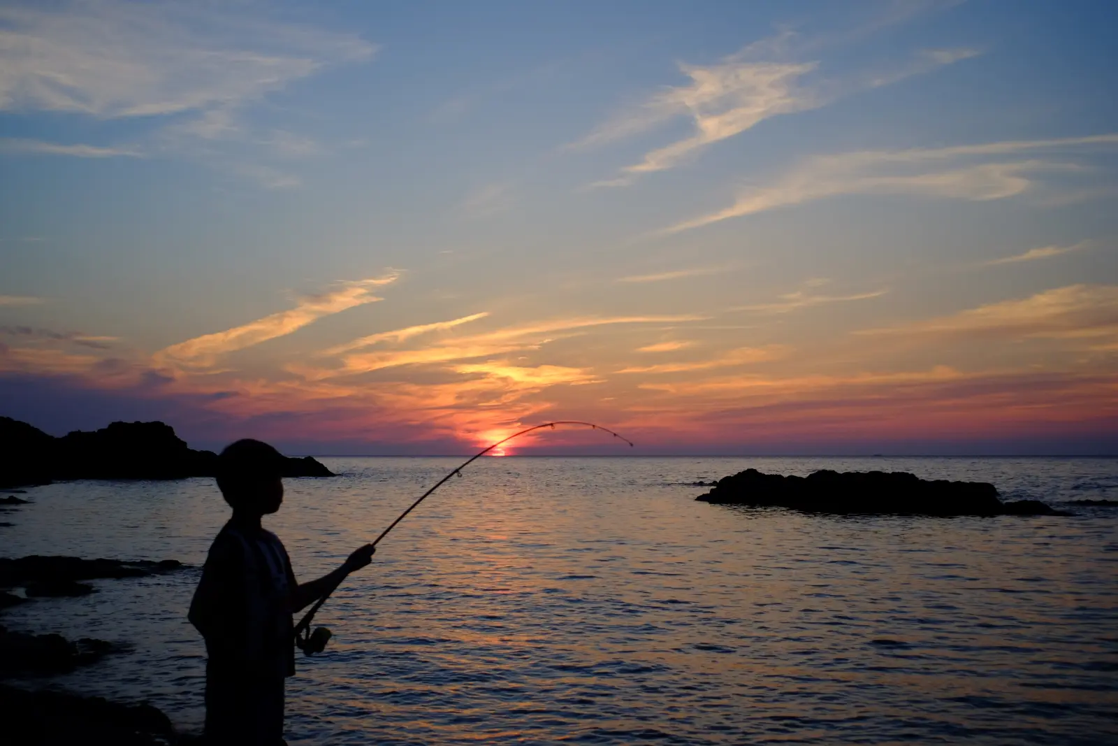 沈む夕日の中釣りを楽しむ