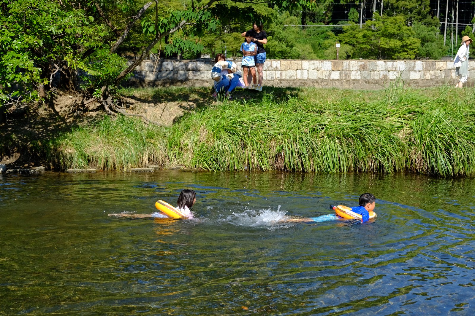 浮輪で川を流れる子どもたち